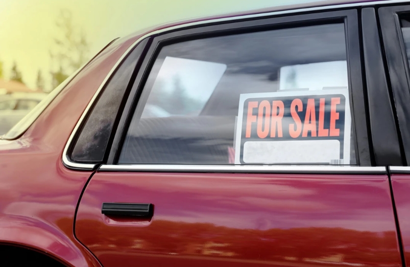 Une voiture d'occasion avec un panneau à vendre dans la fenêtre